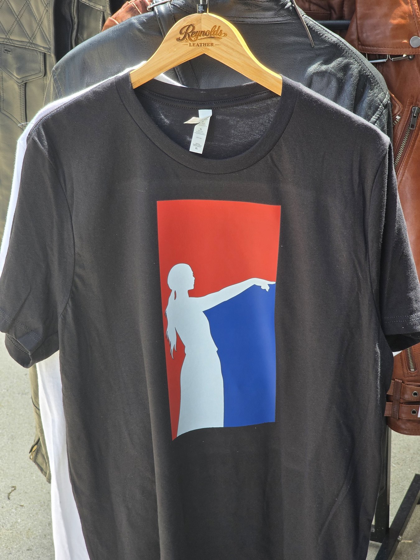 Black custom tee with a red, white, and blue silhouette print on a Reynolds Leather hanger
