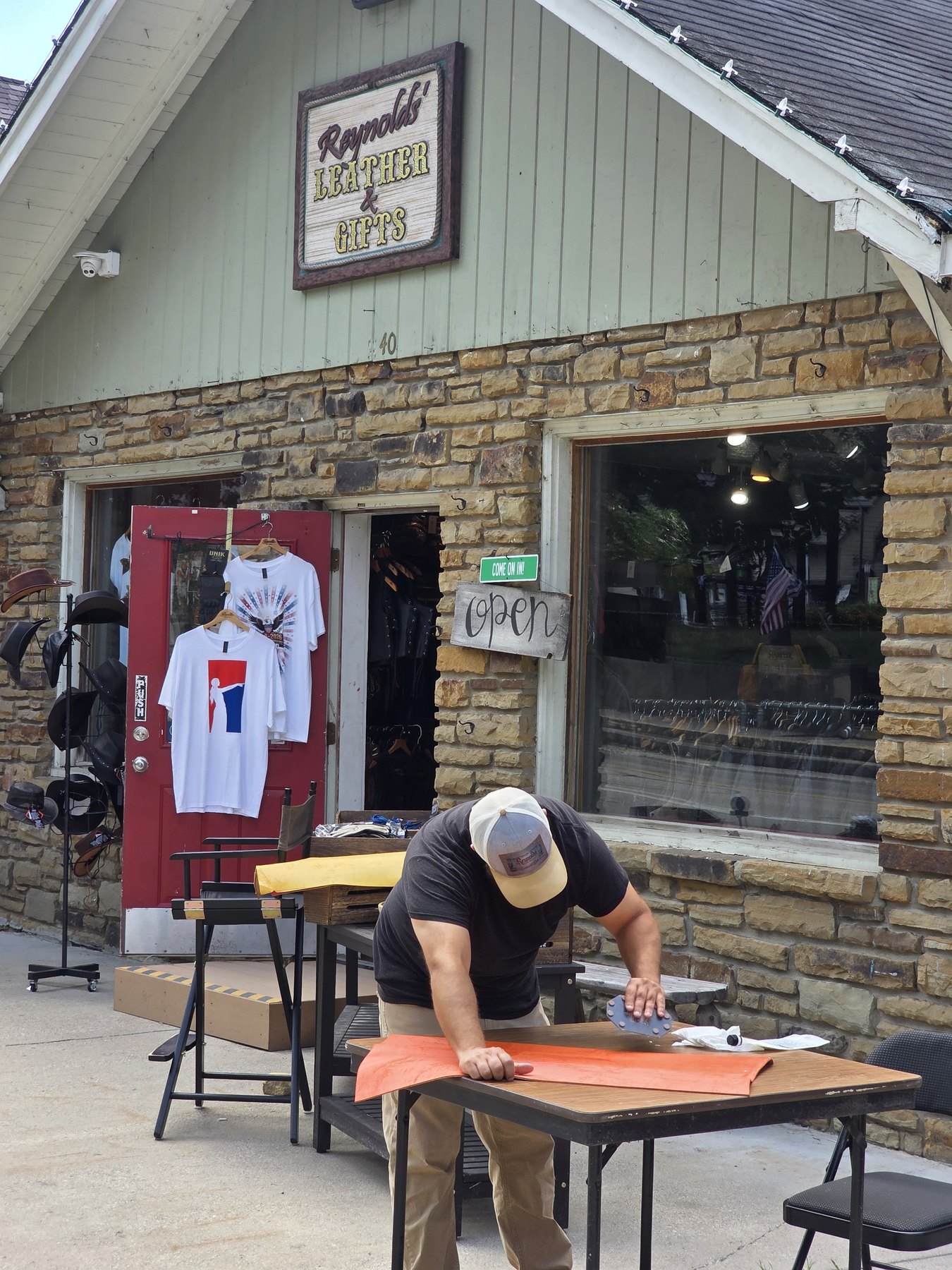 Craftsman working an orange hide at a table outside Reynolds Leather, 40 N Van Buren Street